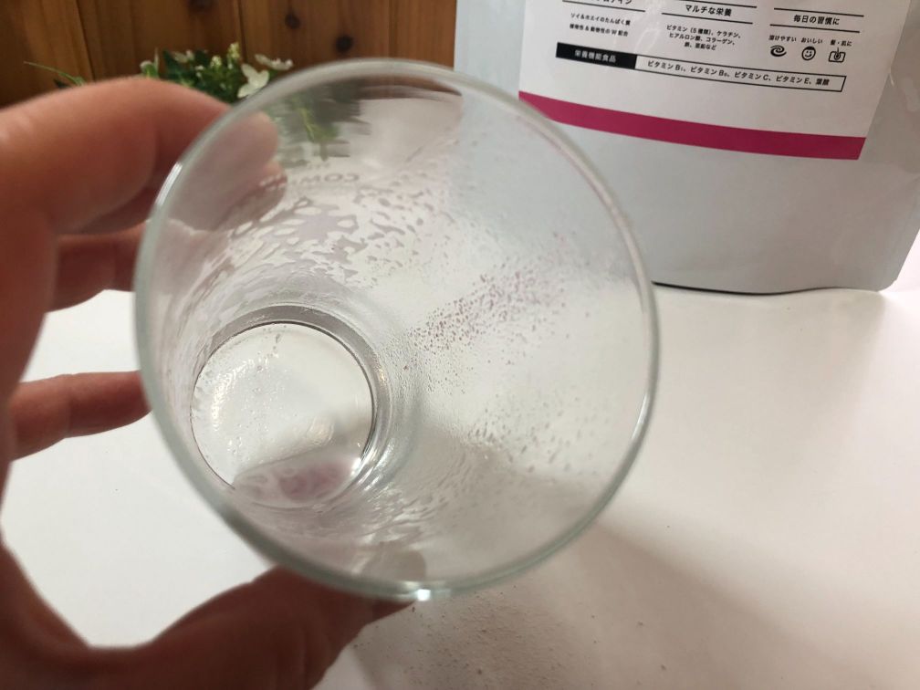 プロテインミックスベリー味を飲んだ後の透明なコップにプロテイン粉末が少し付着している